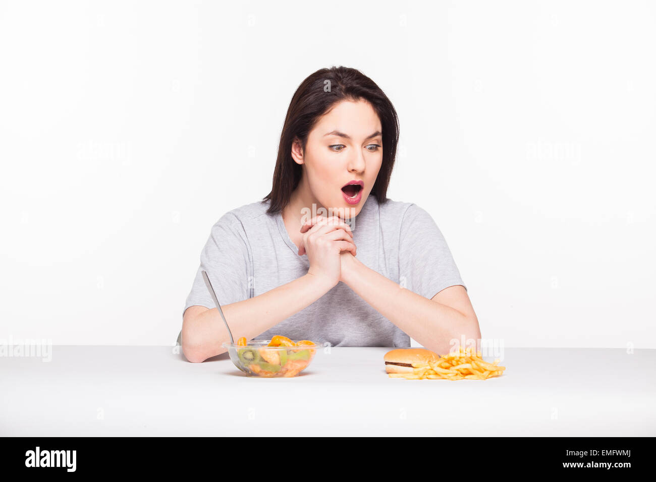 gesunde gegen Junk-Food-Konzept mit einer natürlichen Frau wogenden vor Obst essen und Pommes mit Hamburger, isoliert auf weiss Stockfoto