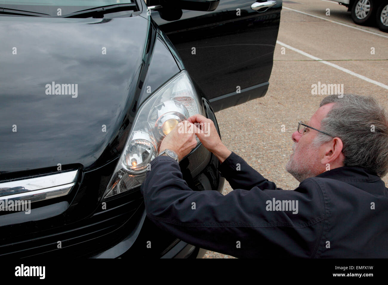 Ein Mann, der Einbau der Scheinwerfer-Strahl-Adapter an die Scheinwerfer eines Autos Stockfoto