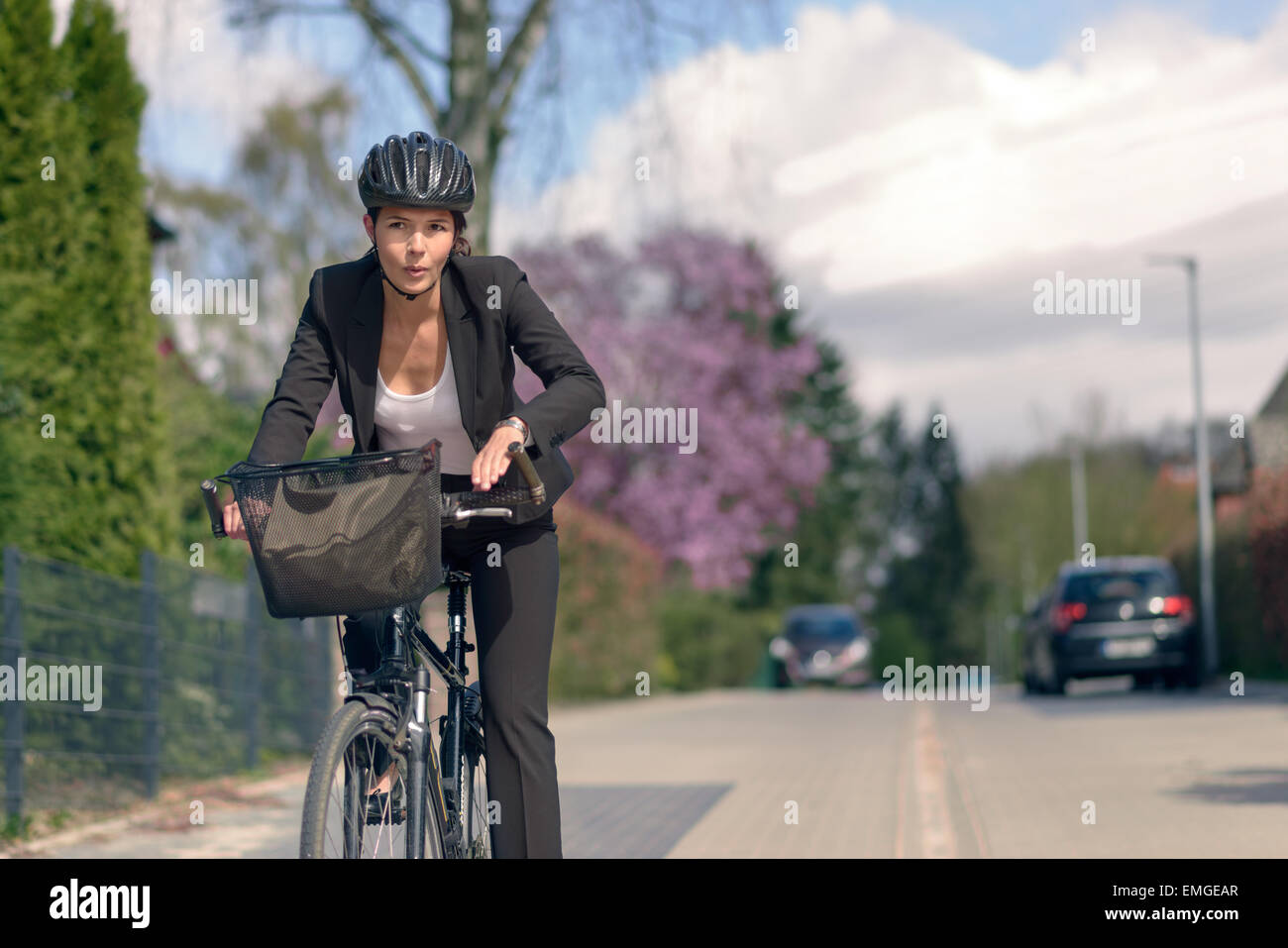 Junge aktive Geschäftsfrau pendeln mit dem Fahrrad mit dem schützenden Helm gehen zu ihrem Büro Stockfoto