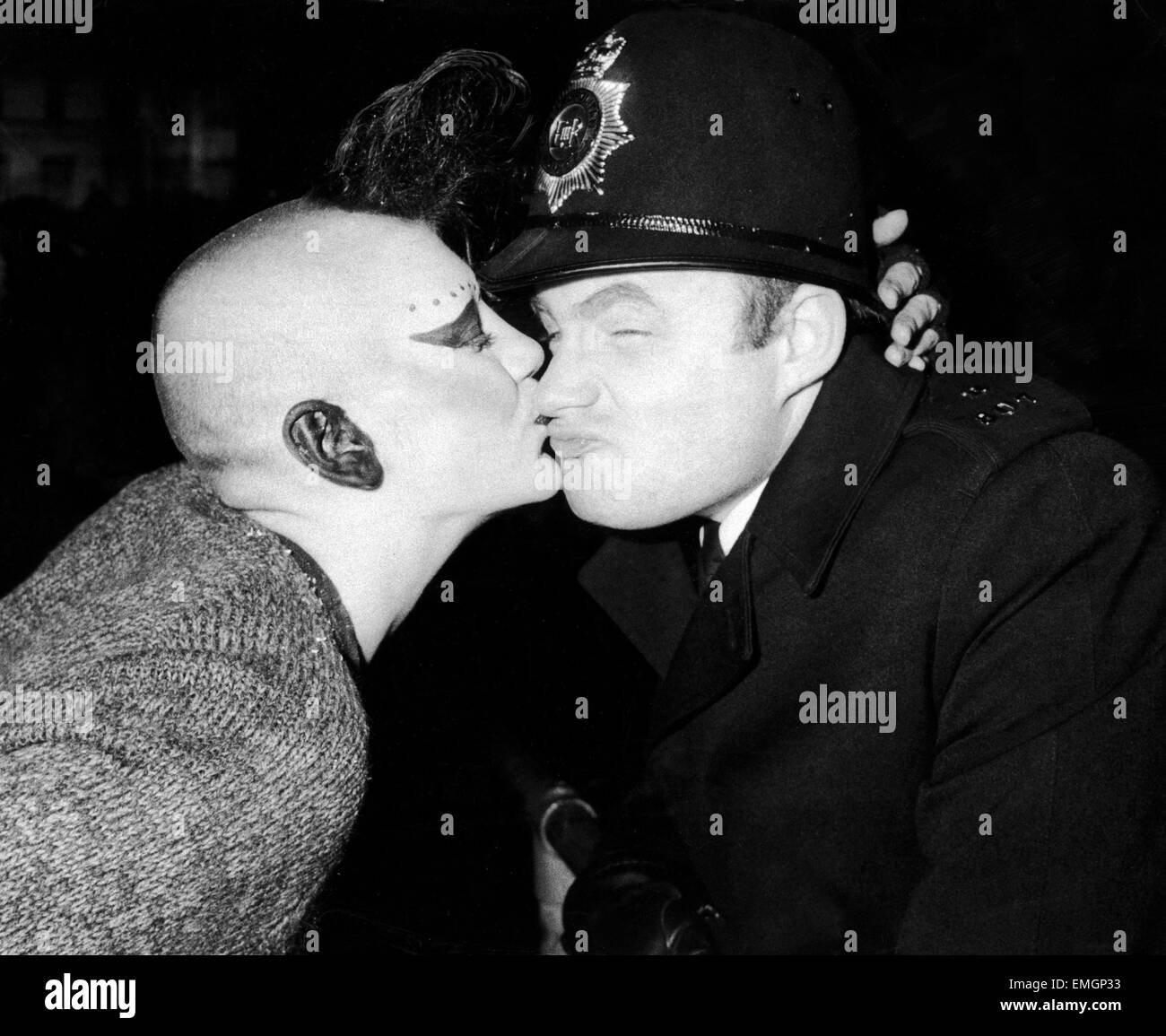 Silvester Reveller 1984. So freundlich: Ein Polizist wird von einem Mädchen-Punk auf dem Trafalgar Square küsste wie 1984 beginnt. 1. Januar 1984 Stockfoto