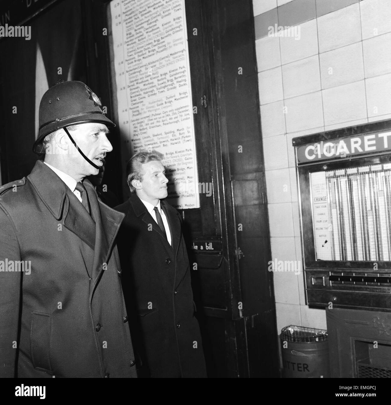 Denis Law, begleitet von einem Polizisten nach seiner Anhörung vor dem Disziplinarrat FA im Royal Victoria Hotel an den Zug an der Victoria Station in Sheffield. 13. Dezember 1964. Stockfoto