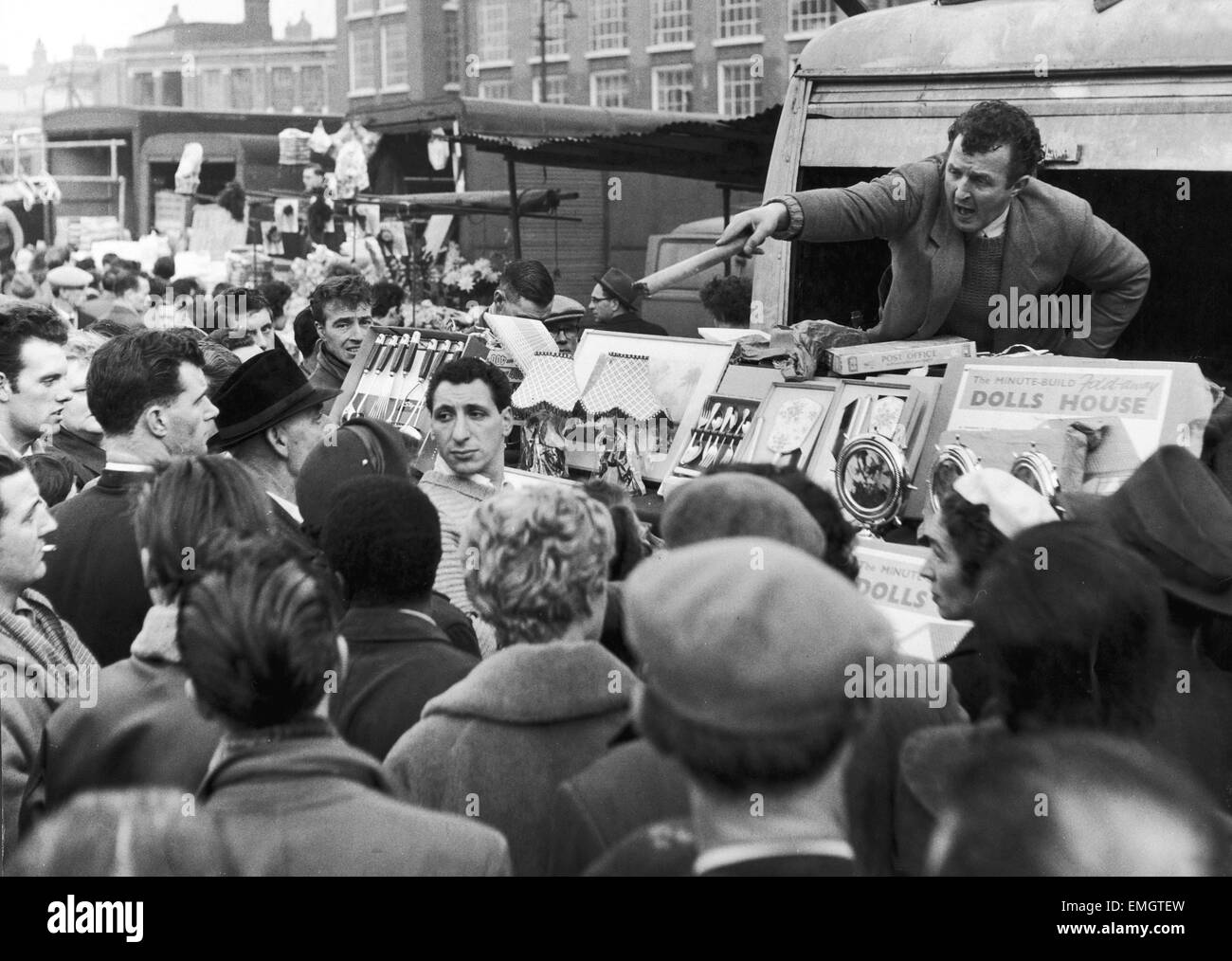 Ein Stall-Inhaber am Petticoat Lane Markt dient ein anderer Kunde als Massen abstammen auf der Suche nach Cnbhristmas präsentiert. 21. Dezember 1958. Stockfoto