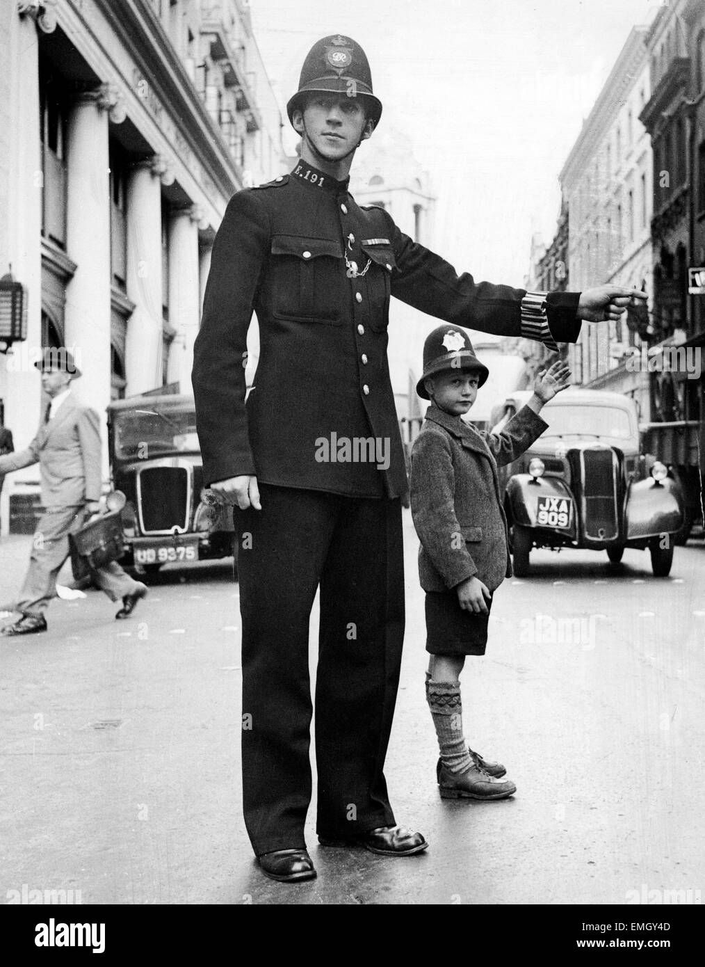 Polizist John Brise im Dienst an der Kreuzung der Bow Street und Long Acre Road in London, Regelung des Verkehrs mit Signalen. Mit ihm steht sieben Jahre alten Terry Jennings, die helfen wollten. 28. Juli 1949. Stockfoto