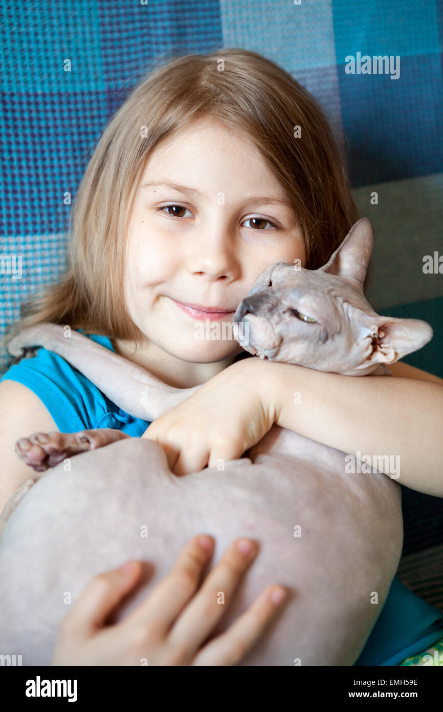 Ziemlich im Vorschulalter Mädchen umarmen Sphynx Katze auf Sofa Stockfoto