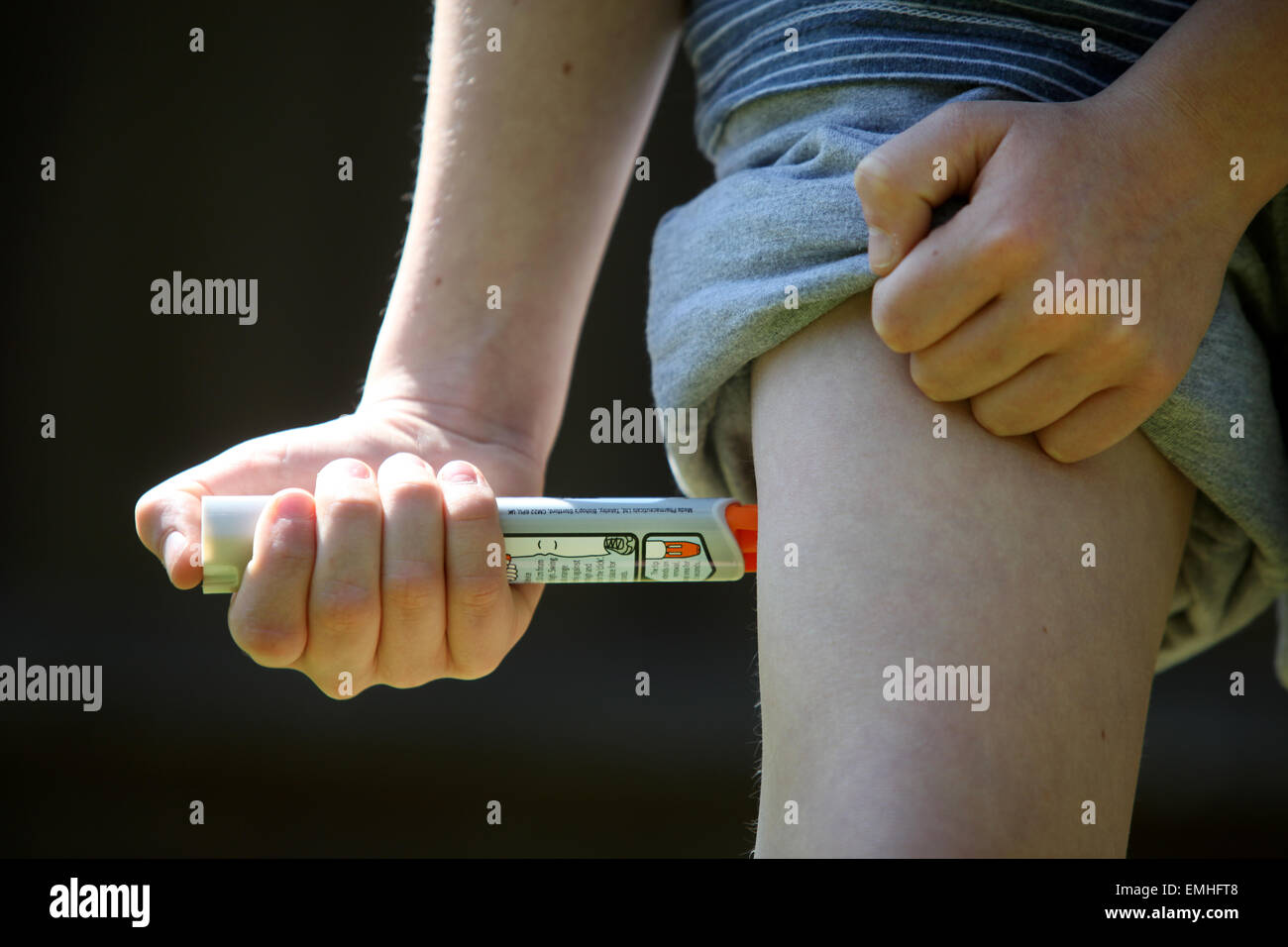 Ein Junge mit einem Epipen an seinem Oberschenkel zeigen was tun bei einem anaphylaktischen Schock Stockfoto