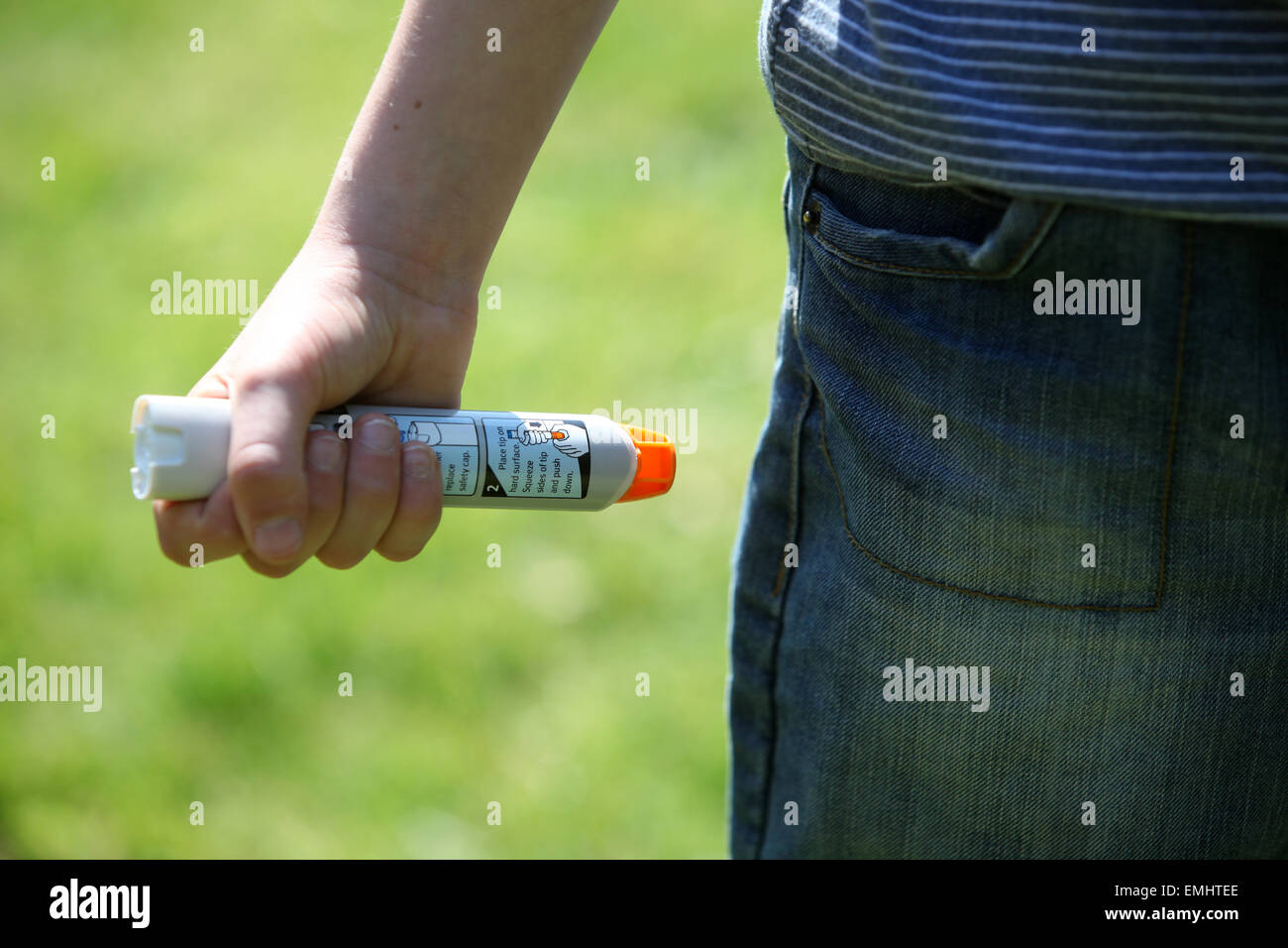 Ein Junge mit einem Epipen an seinem Oberschenkel zeigen was tun bei einem anaphylaktischen Schock Stockfoto