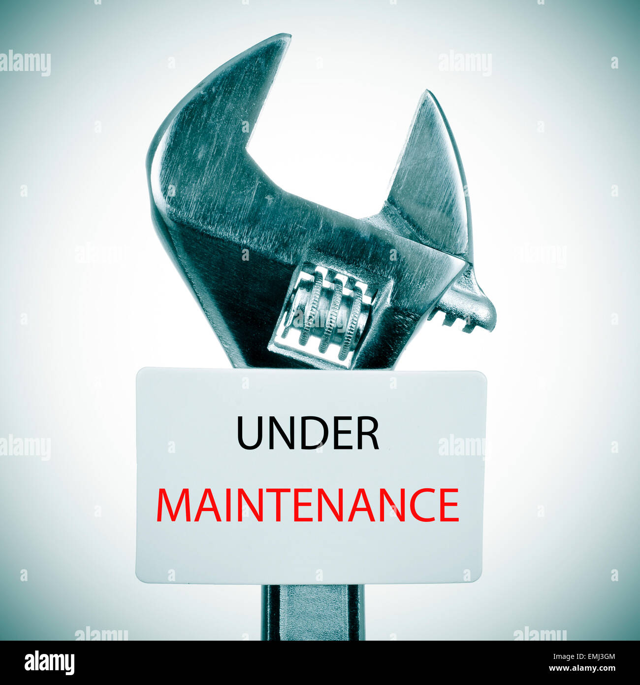 Nahaufnahme von einem verstellbaren Schraubenschlüssel und ein Schild mit dem Text unter Wartung geschrieben, mit einer leichten Vignette hinzugefügt Stockfoto