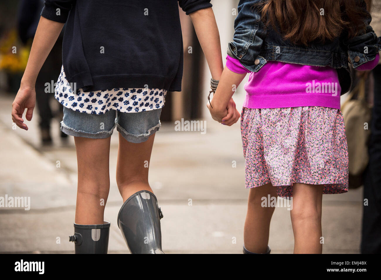 Zwei junge Mädchen Hand in Hand während des Gehens auf Gehsteig, close-up-Rückansicht Stockfoto