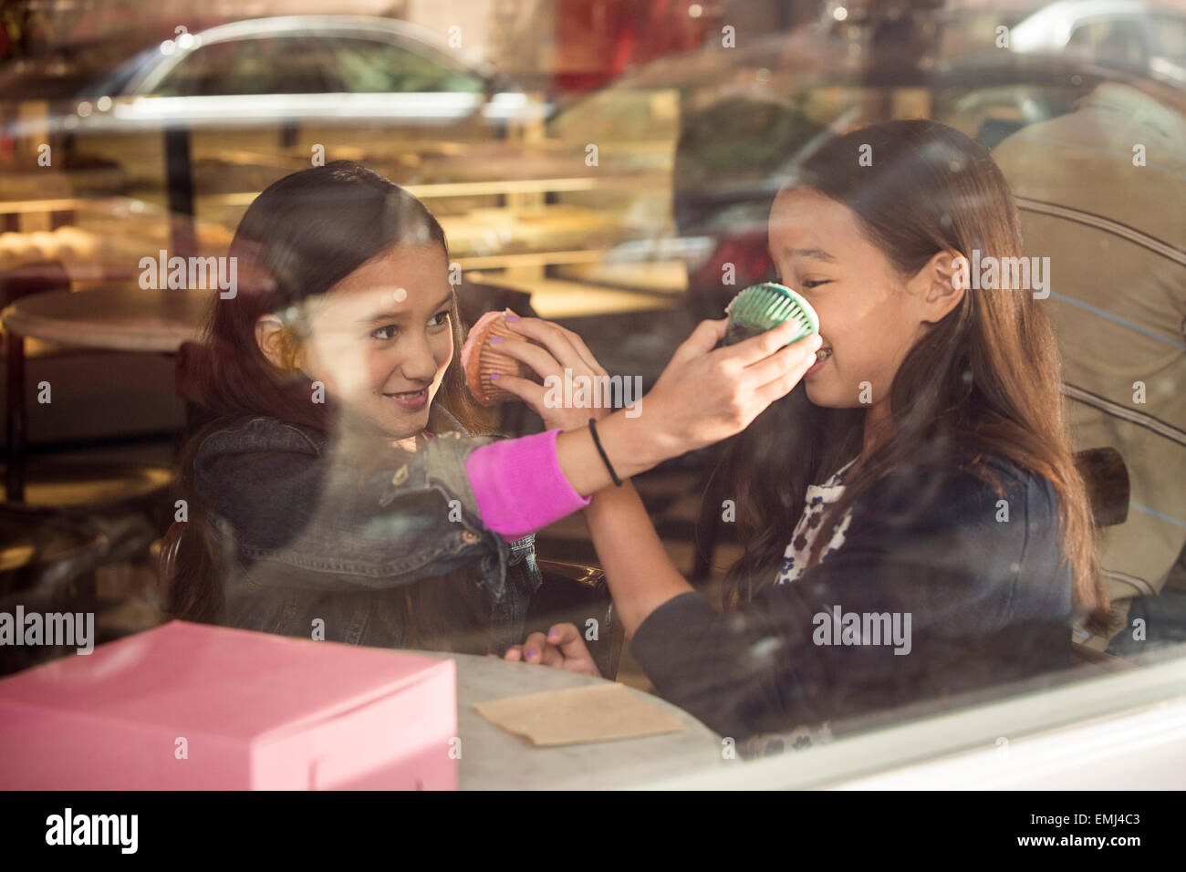 Zwei junge Mädchen, die Cupcakes in einander ins Gesicht zu drücken Stockfoto