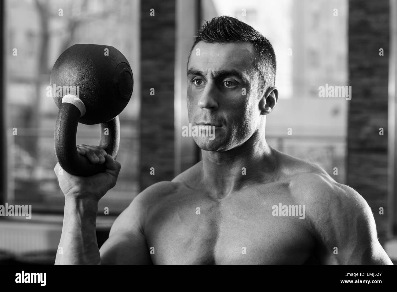 Schwarz-weiß-Porträt eines Bodybuilders mit Wasserkocher Ball im Fitness-Studio Stockfoto