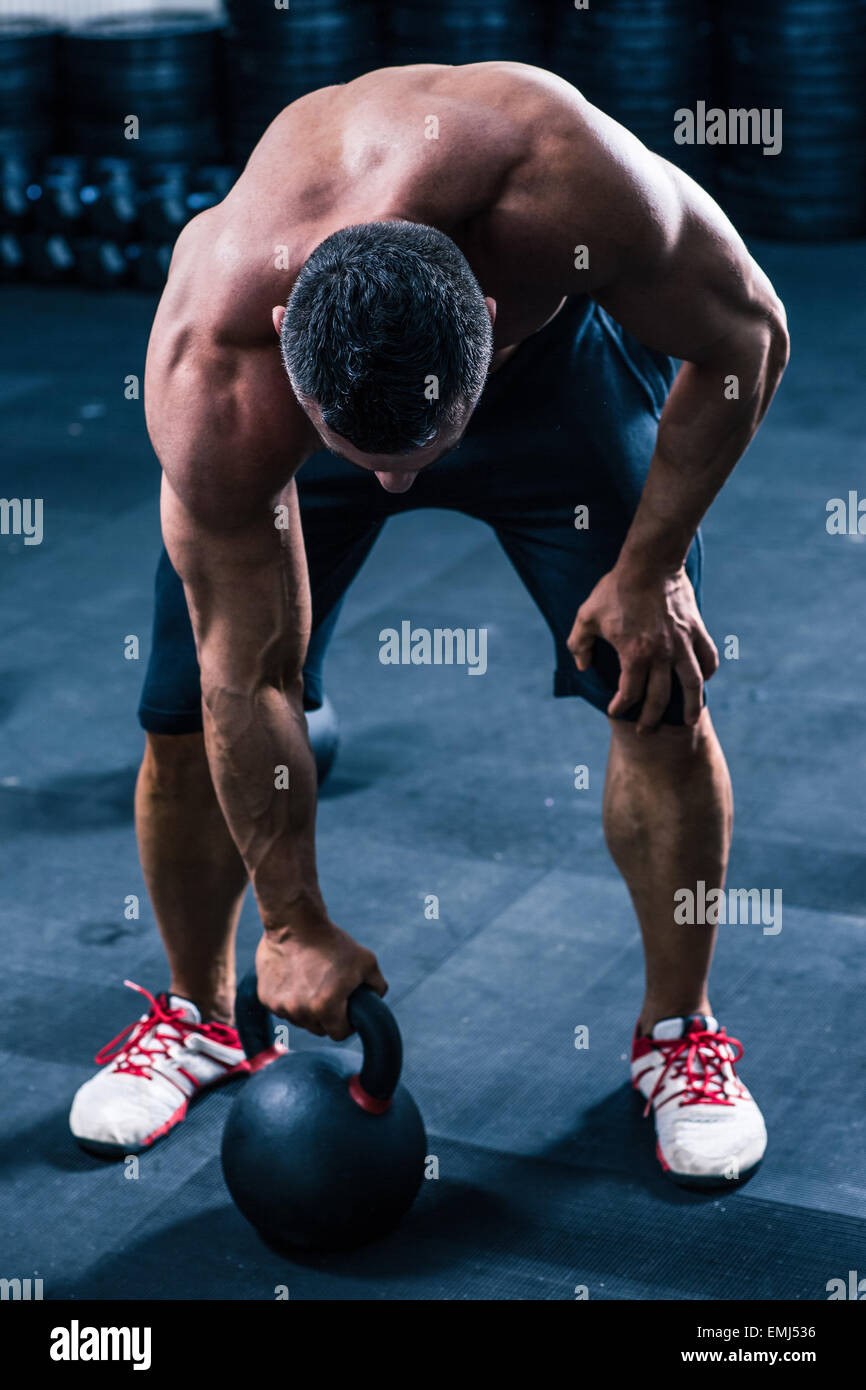 Muskulöser Mann Training mit Wasserkocher Ball in Turnhalle Stockfoto