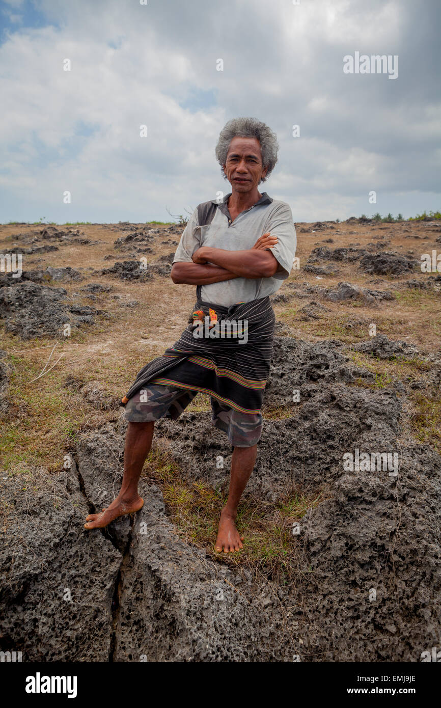 Porträt eines Mannes, der während der Trockenzeit auf einer felsigen Savanne in Sumba steht, einer Insel, die regelmäßig von Dürre in Ost-Nusa Tenggara, Indonesien, heimgesucht wird. Stockfoto