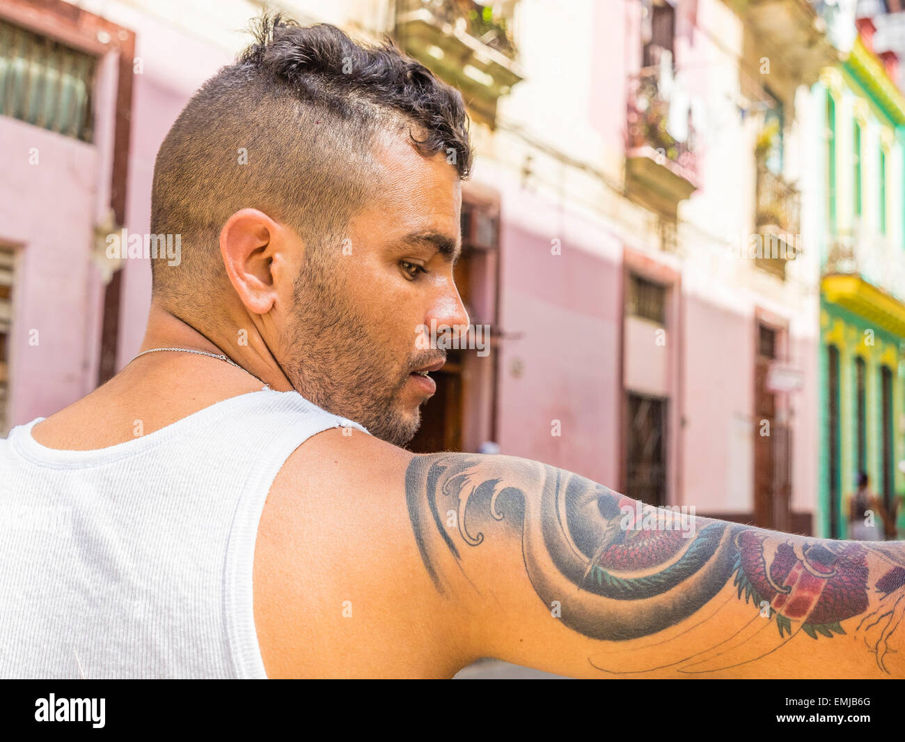 Ein 20-29 jährige kubanische Hispanic Mann mit einem trendigen Haarschnitt zeigt seine tätowierten Oberarm in Havanna Vieja. Stockfoto