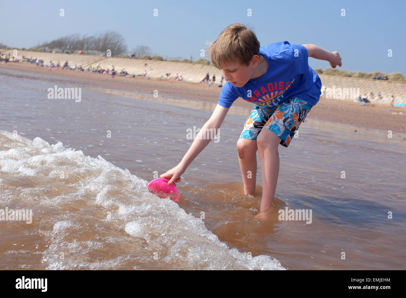 Ein Junge sammeln Wasser in einem Eimer an einem UK-Strand Stockfoto