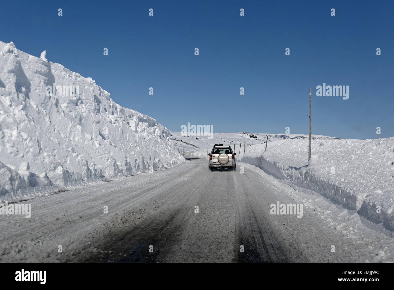 Auto Straßenfahrt Eastbound E7 über Hardangervidda, Norwegen, mit hoher Schneewände rund um die Straße. Stockfoto