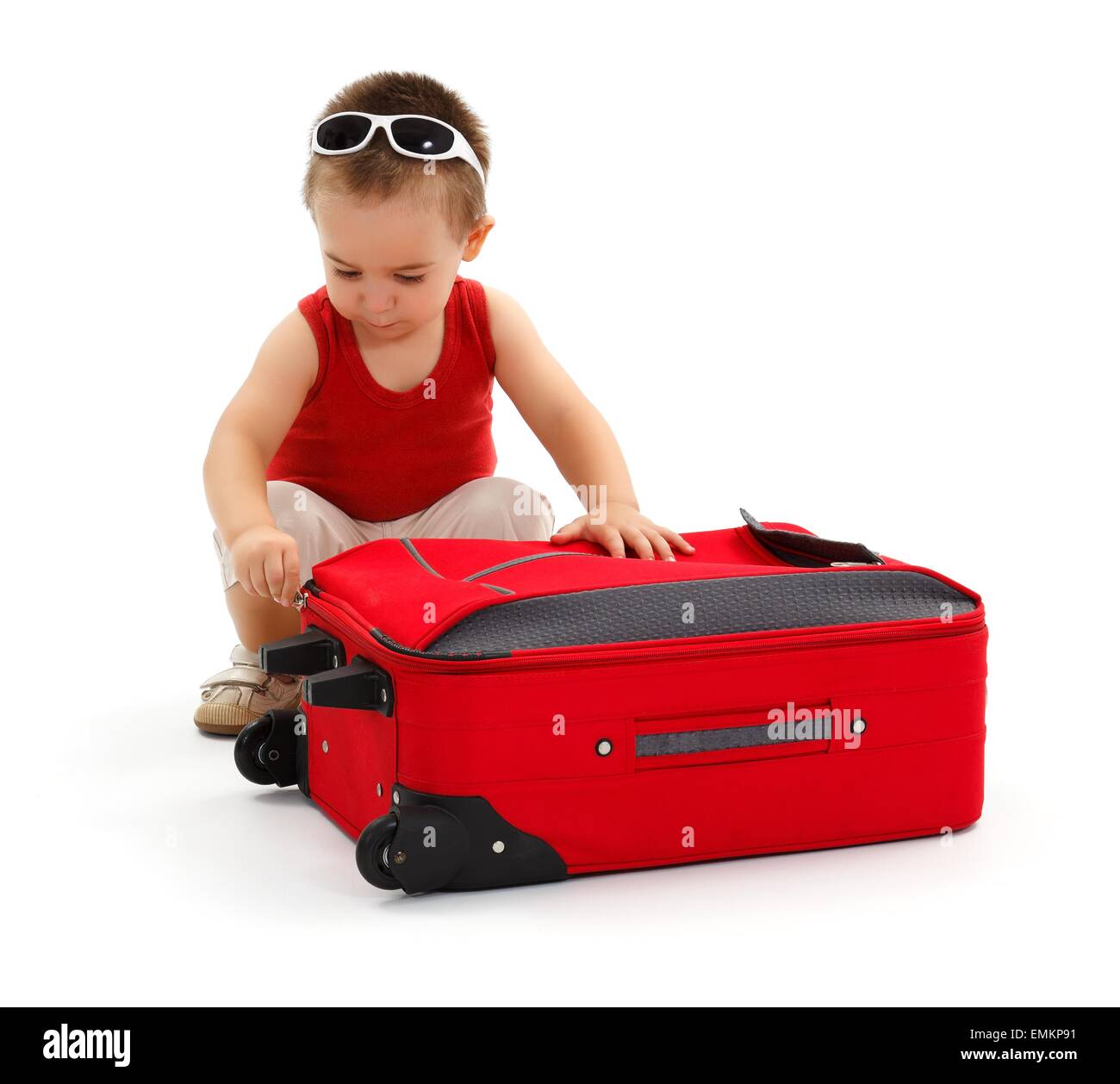 Kleiner Junge in Sonnenbrille, Vorbereitung auf Urlaubsreise, öffnen oder schließen roten Koffer Stockfoto