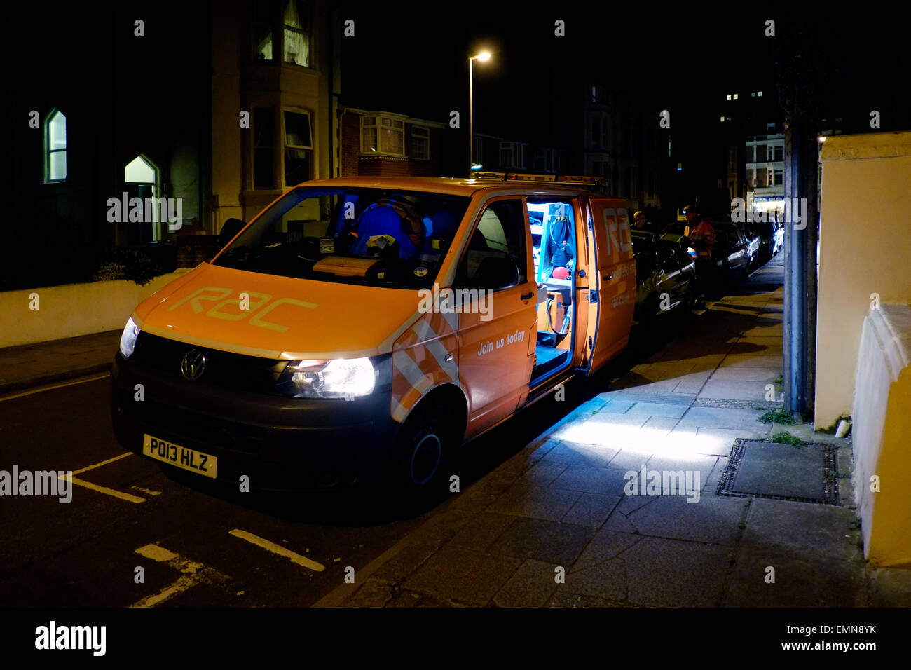 RAC-van in dunklen Straße geparkt, wie die Mechaniker sich Autobesitzer eine gebrochene unterstützt Stockfoto