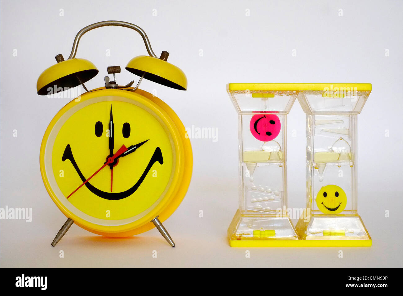 leuchtend gelbe traditionellen Wecker mit Smiley-Gesicht neben Öl angetrieben timer Stockfoto