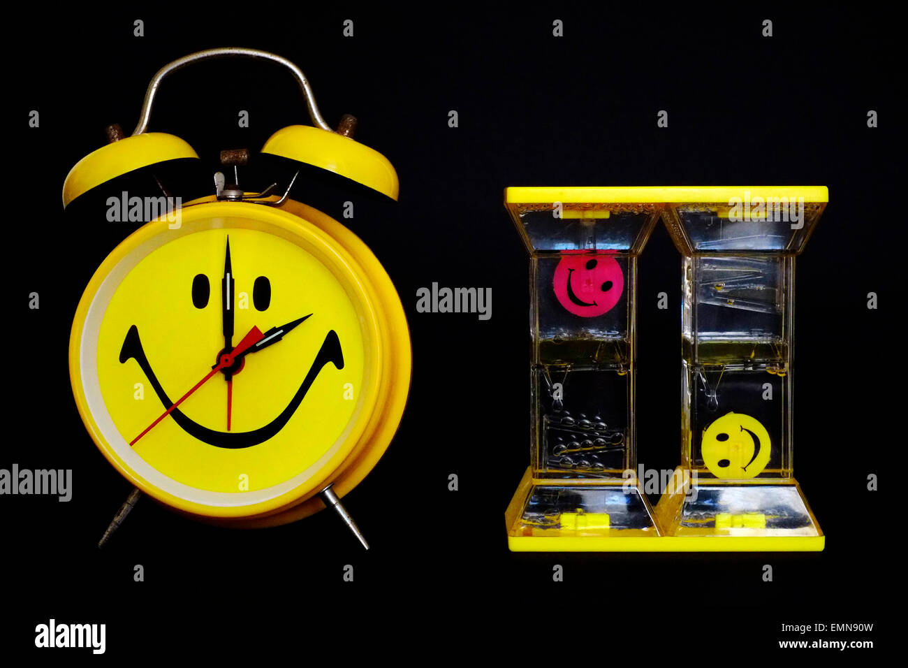 leuchtend gelbe traditionellen Wecker mit Smiley-Gesicht neben Öl angetrieben timer Stockfoto