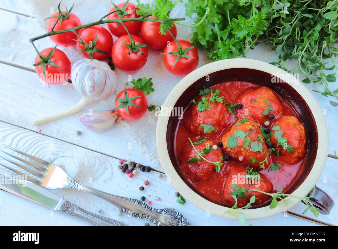 Schale mit Fleischbällchen in Tomatensauce mit Kräutern auf einem Holztisch Stockfoto