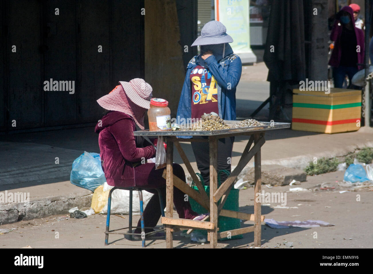 Zwei Frauen warten auf Kunden für Schnecken, die sie als Straße Nahrung auf eine Stadt Straße in Kampong Cham, Kambodscha verkaufen. Stockfoto