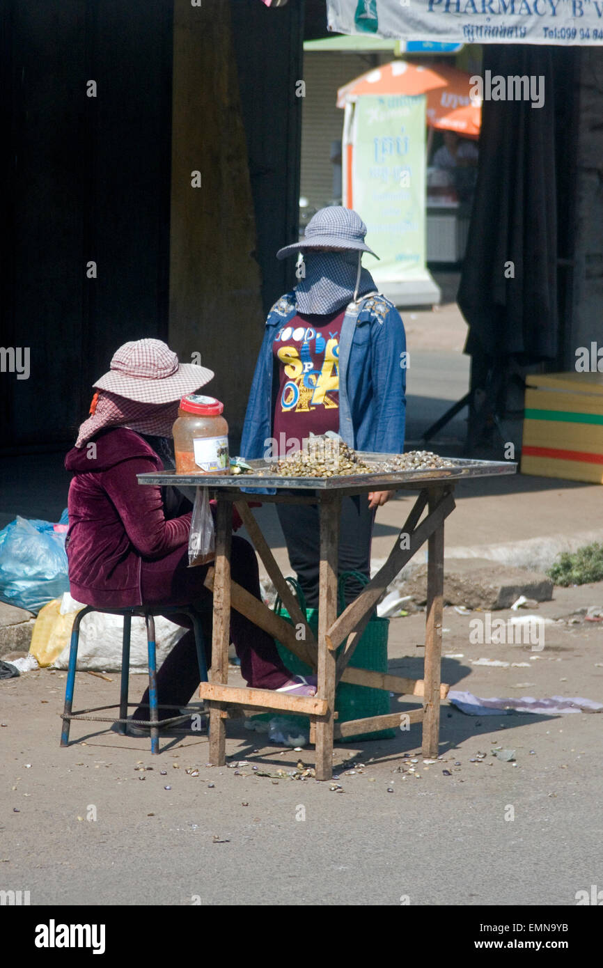 Zwei Frauen warten auf Kunden für Schnecken, die sie als Straße Nahrung auf eine Stadt Straße in Kampong Cham, Kambodscha verkaufen. Stockfoto