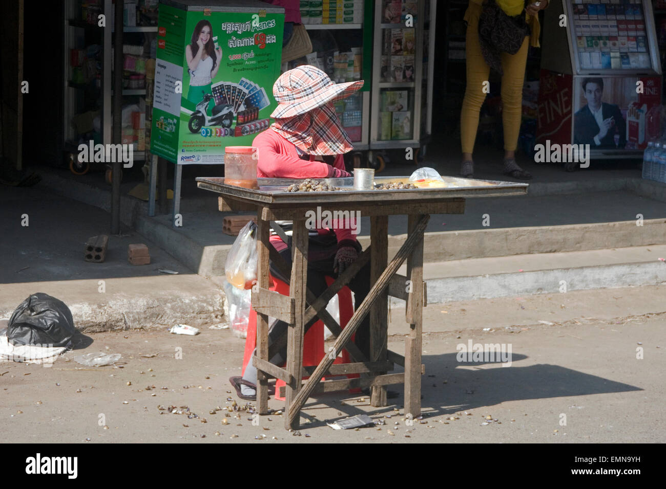 Eine Frau wartet auf Kunden für Schnecken, die sie als Straße Nahrung auf eine Stadt Straße in Kampong Cham, Kambodscha verkaufen. Stockfoto