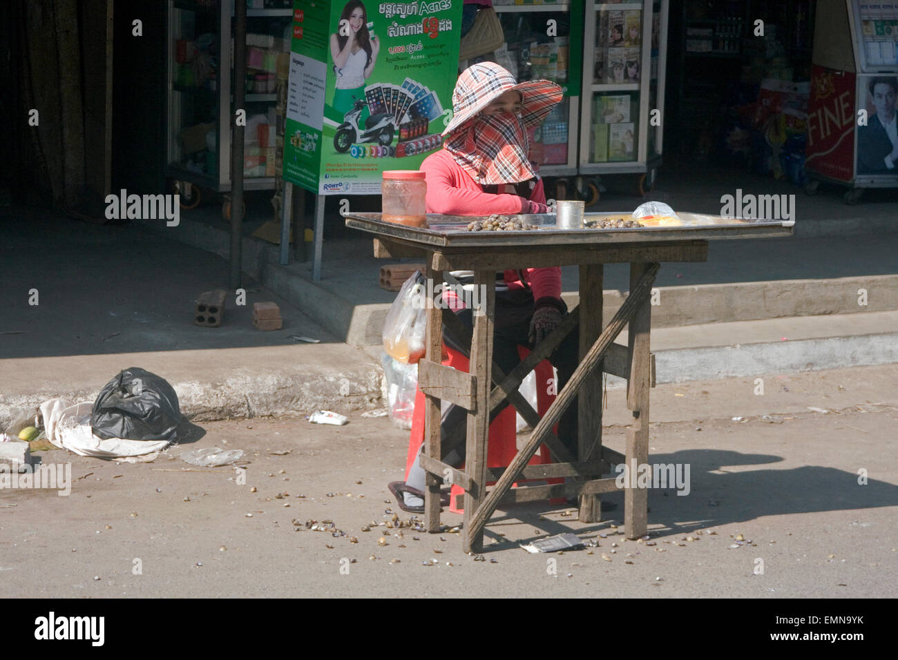 Eine Frau wartet auf Kunden für Schnecken, die sie als Straße Nahrung auf eine Stadt Straße in Kampong Cham, Kambodscha verkaufen. Stockfoto