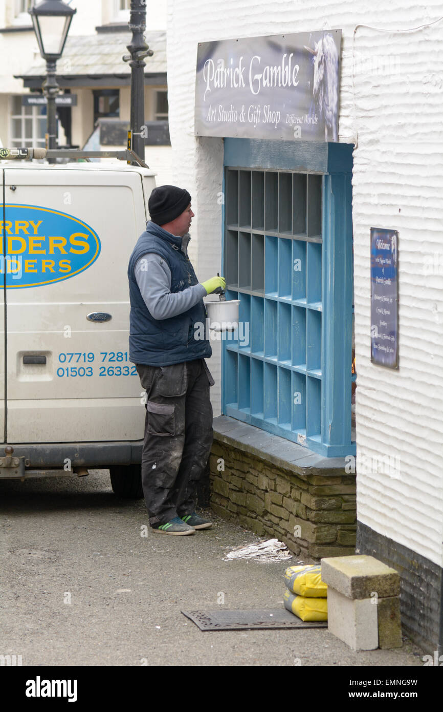 Mann Malerei Windows der Geschenkeladen in Polperro, Cornwall, England Stockfoto