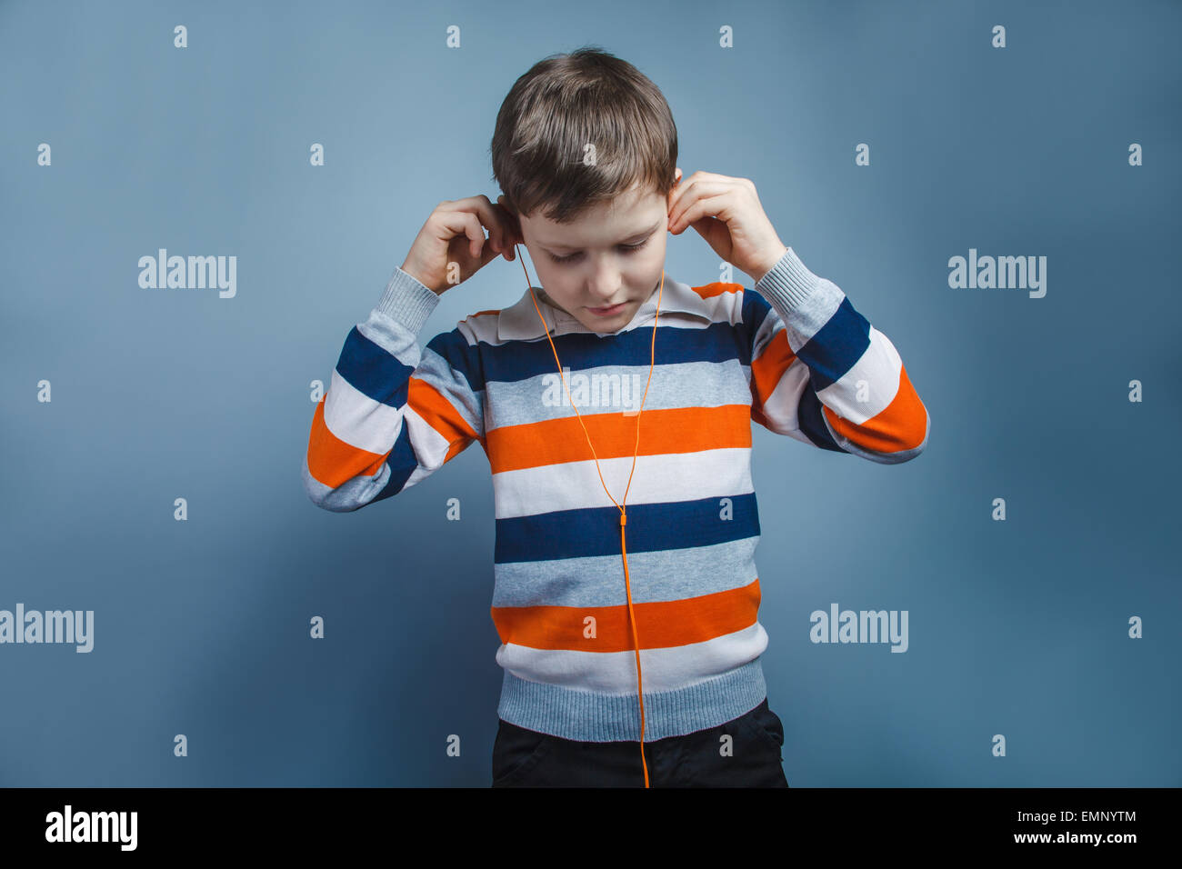 Europäisch anmutende junge von zehn Jahren Musikhören mit Kopfhörer auf grauem Hintergrund Stockfoto