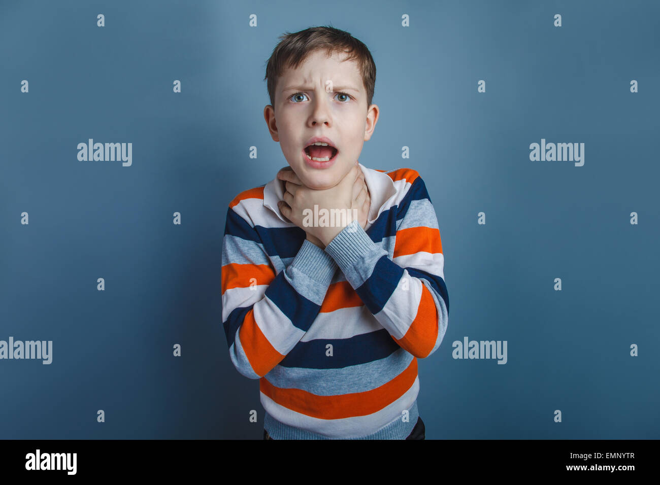 Europäisch anmutende junge von zehn Jahren erwürgt sich Hände auf einem grauen Hintergrund Stockfoto
