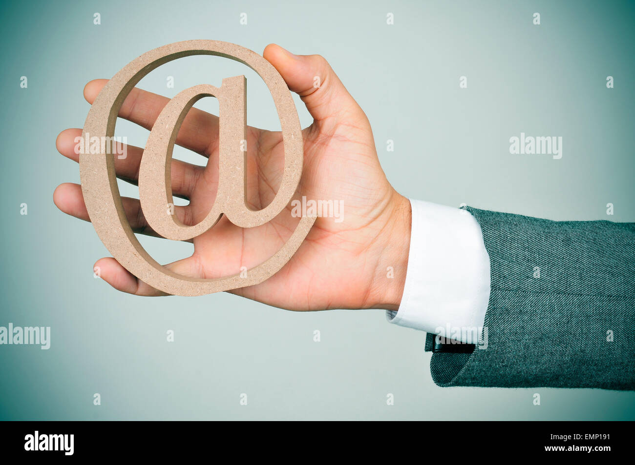 Nahaufnahme der Hand eines jungen kaukasischen Geschäftsmann in einem grauen Anzug zeigt am Schild aus Holz Stockfoto