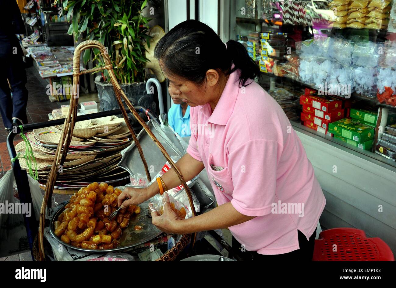 Bangkok, Thailand: Thai Frau verkaufen gebratene Bananen aus ihrem kleinen Warenkorb auf belebten Thanon Chakrabongse Stockfoto