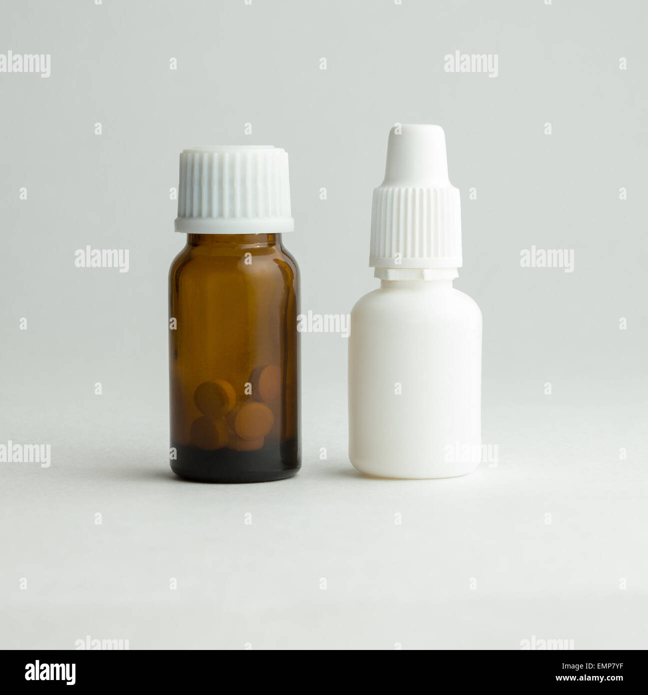 Kleine Flasche aus dunklem Glas mit einem weißen Deckel und Tabletten. Stockfoto