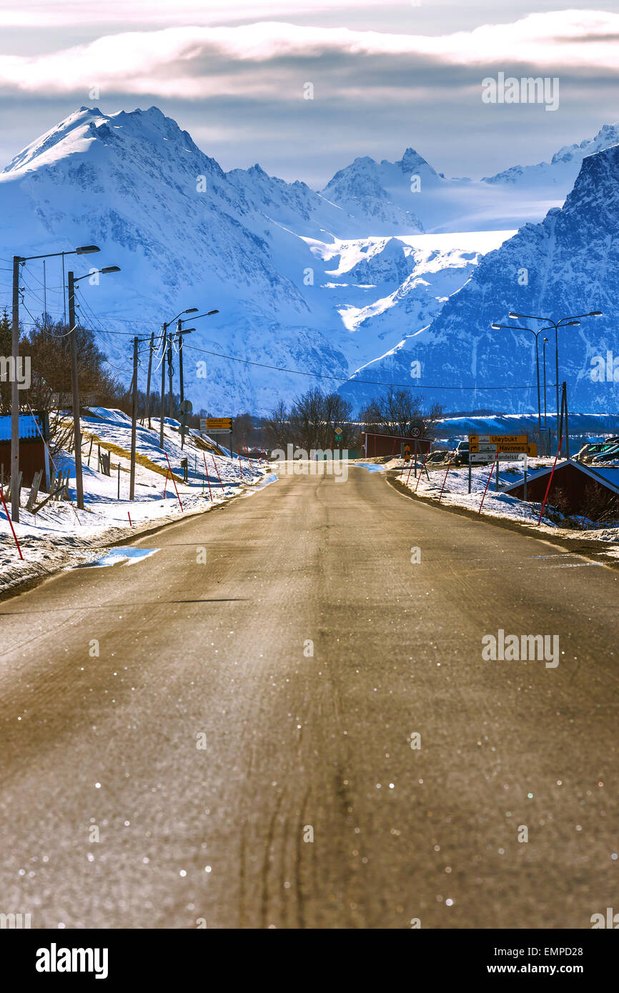 Eine sonnige norwegische Landschaft mit einer Landstraße im Vordergrund und Snowy und blau Gebirge im Hintergrund. Stockfoto