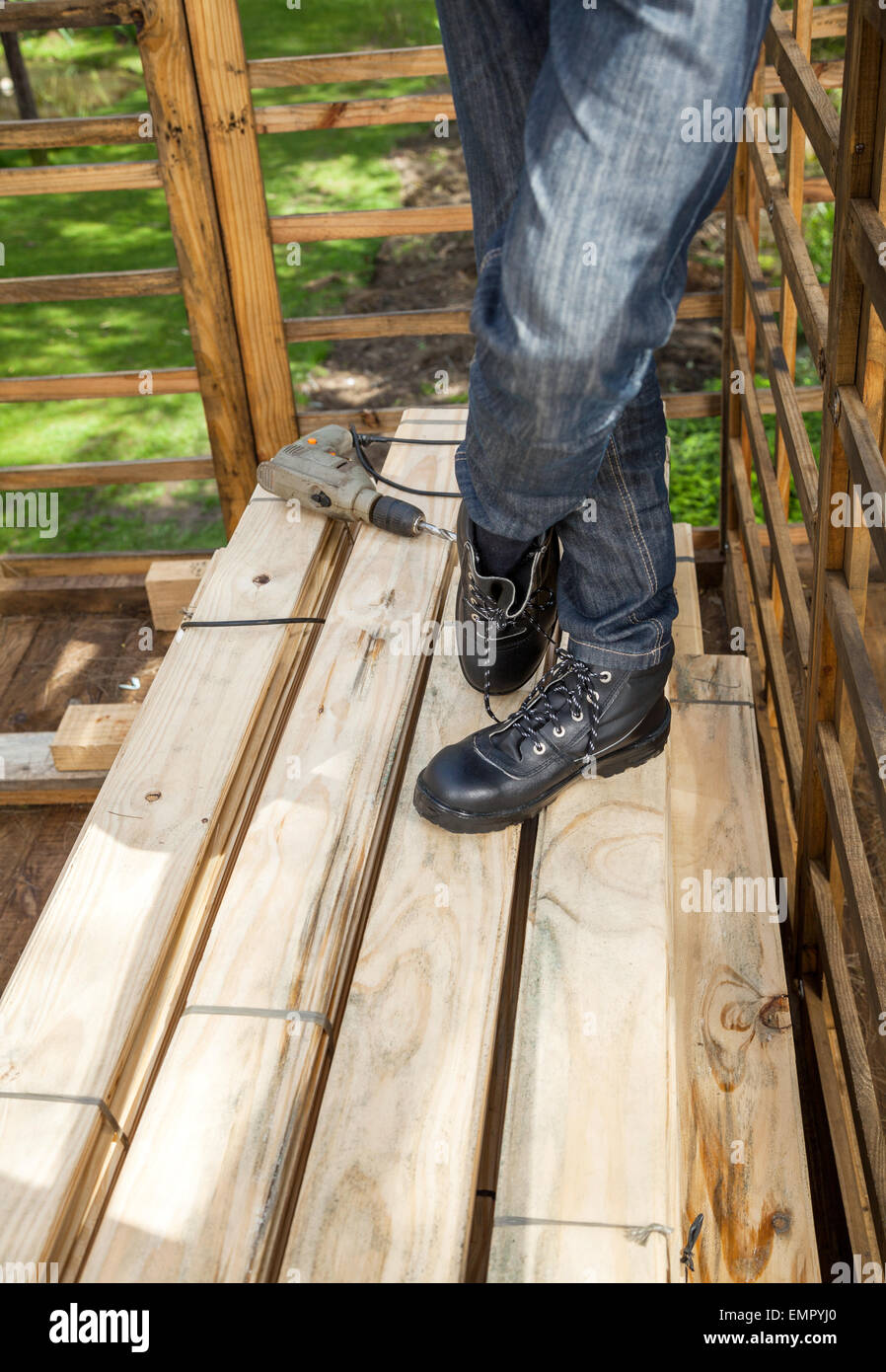 Bauarbeiter durch Drill auf gestapelten Holzbohlen stehen Stockfoto