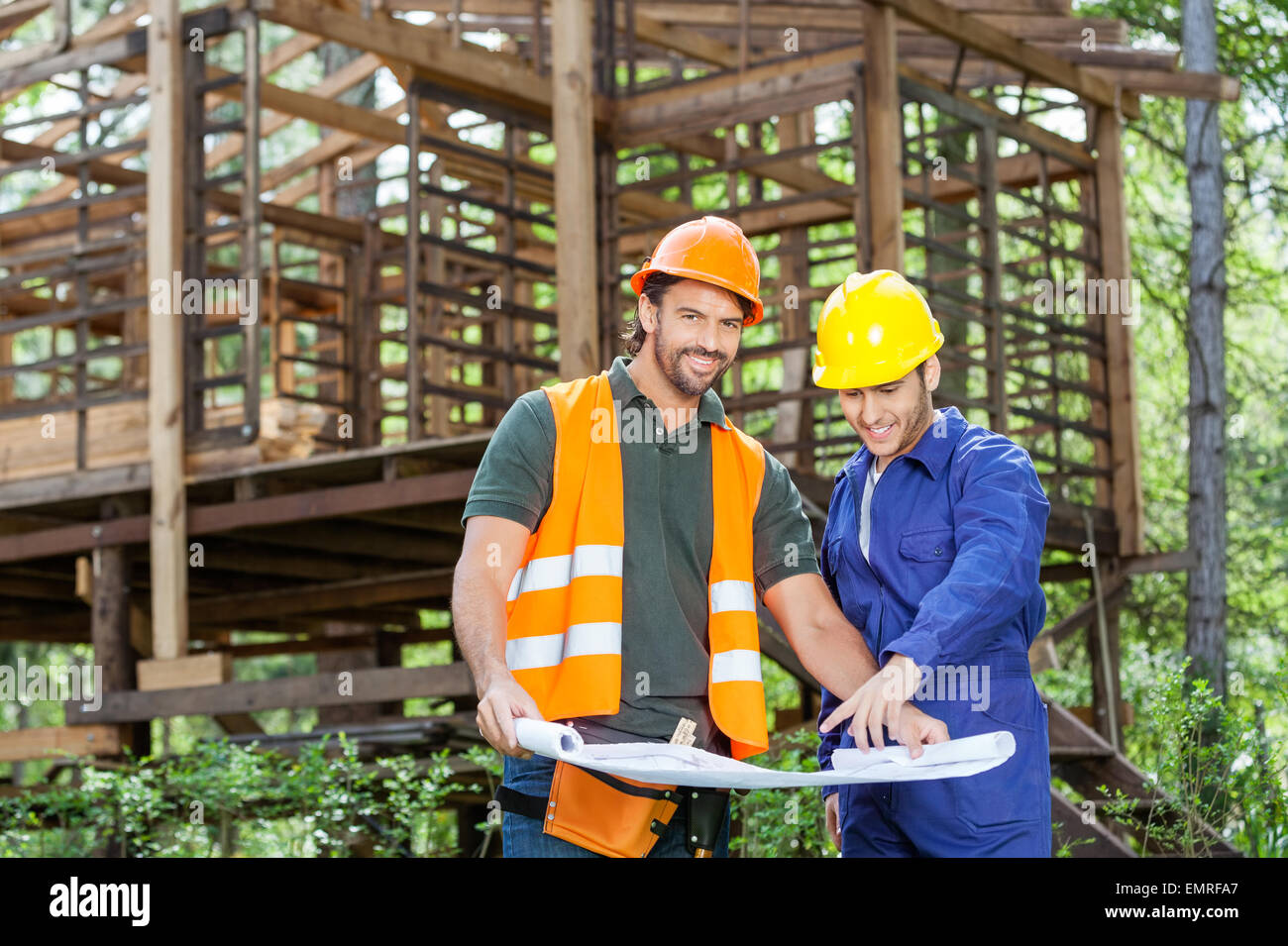 Lächelnde Architekten mit Blueprint auf Baustelle Stockfoto
