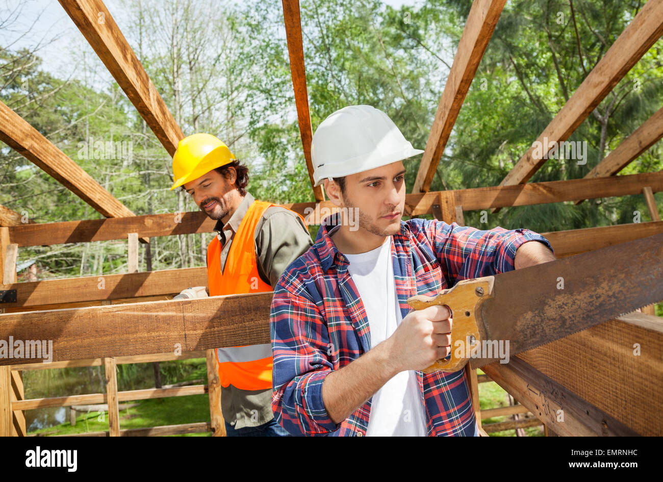 Construction Worker Schneiden von Holz mit Handsäge am Standort Stockfoto