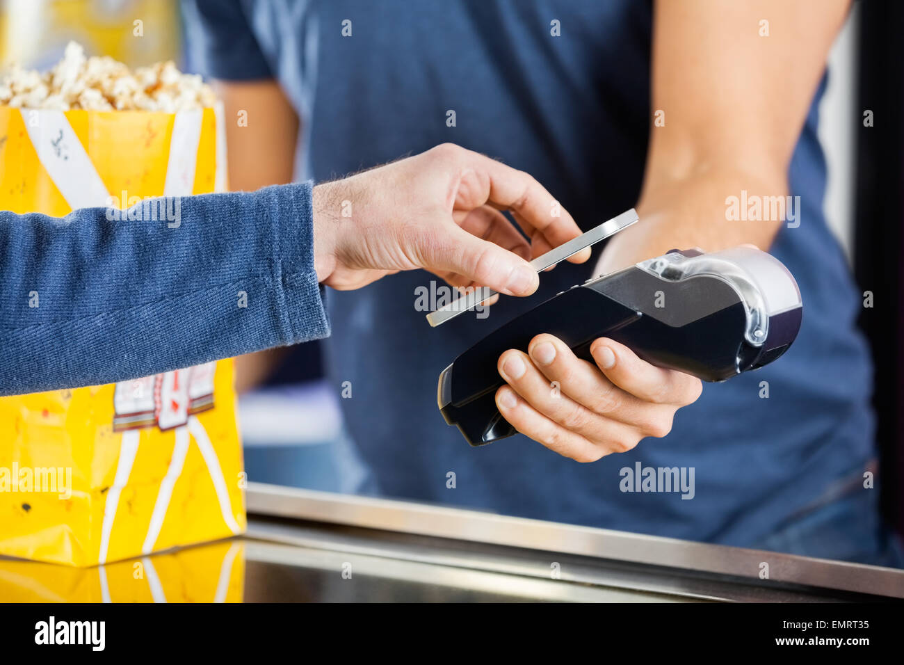 Mann, der Zahlung per NFC-Technologie im Kino Stockfoto