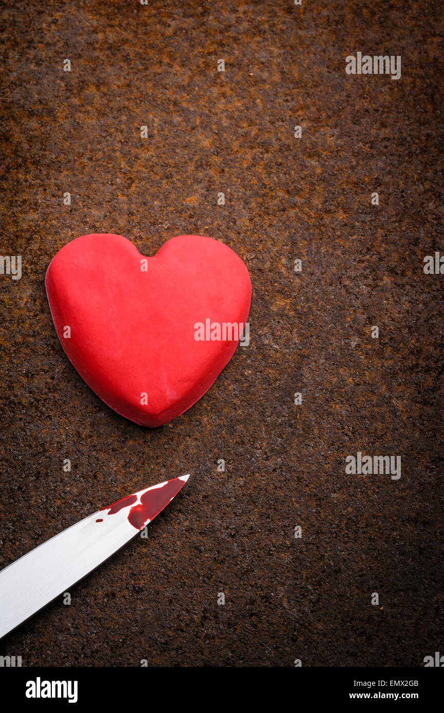 Blutverschmierte Messer und Fondant Vereisung Herz auf Grunge, rostigen Hintergrund. Stockfoto