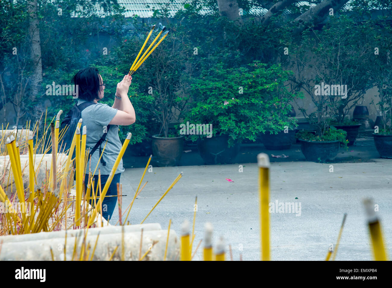 Eine Menge Räucherstäbchen brennen in Gefäße, mit einer Frau zu beten Stockfoto