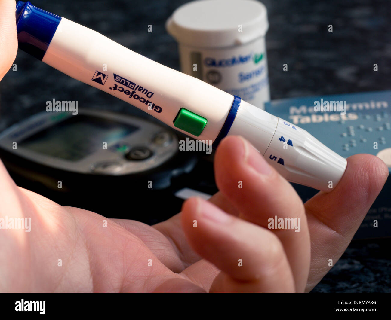 Ein Diabetes-Finger-Pfriem wird in einen Finger mit anderen Diabetes-Behandlungen im Hintergrund injiziert. Stockfoto