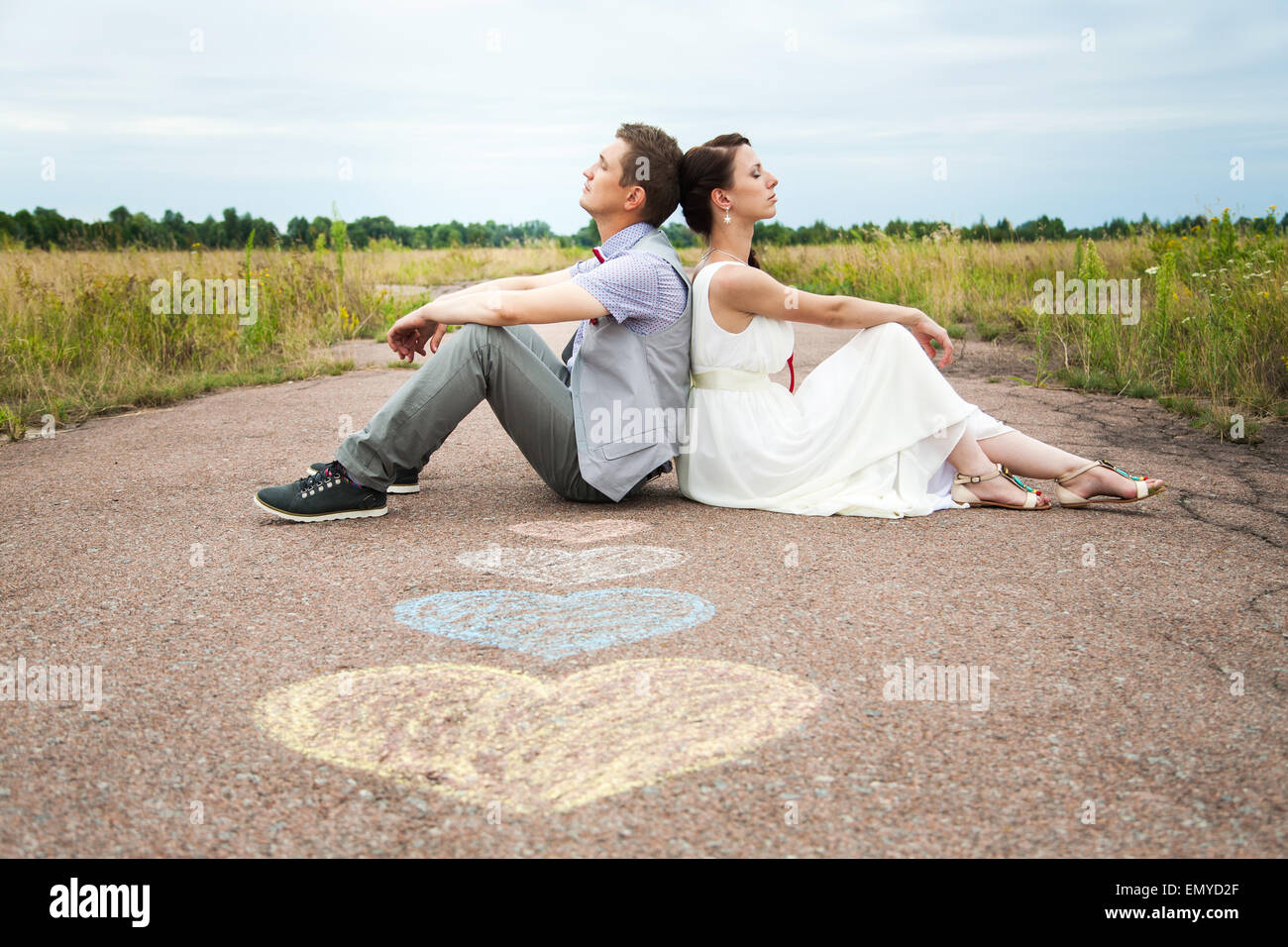 Hochzeitspaar auf Boden saßen. lieben Sie Symbole auf Asphalt. Herzen. Menschen in der Liebe. glückliche Braut und Bräutigam Porträts Stockfoto