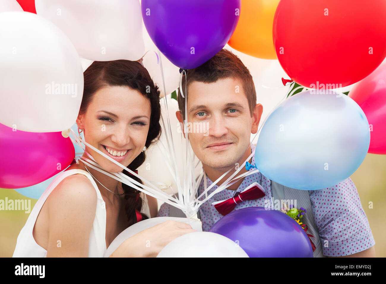 Kopf und Schultern Porträt des fröhlichen Brautpaar. Mann und Frau, die viele bunte Latex Luftballons in den Händen halten. Stockfoto