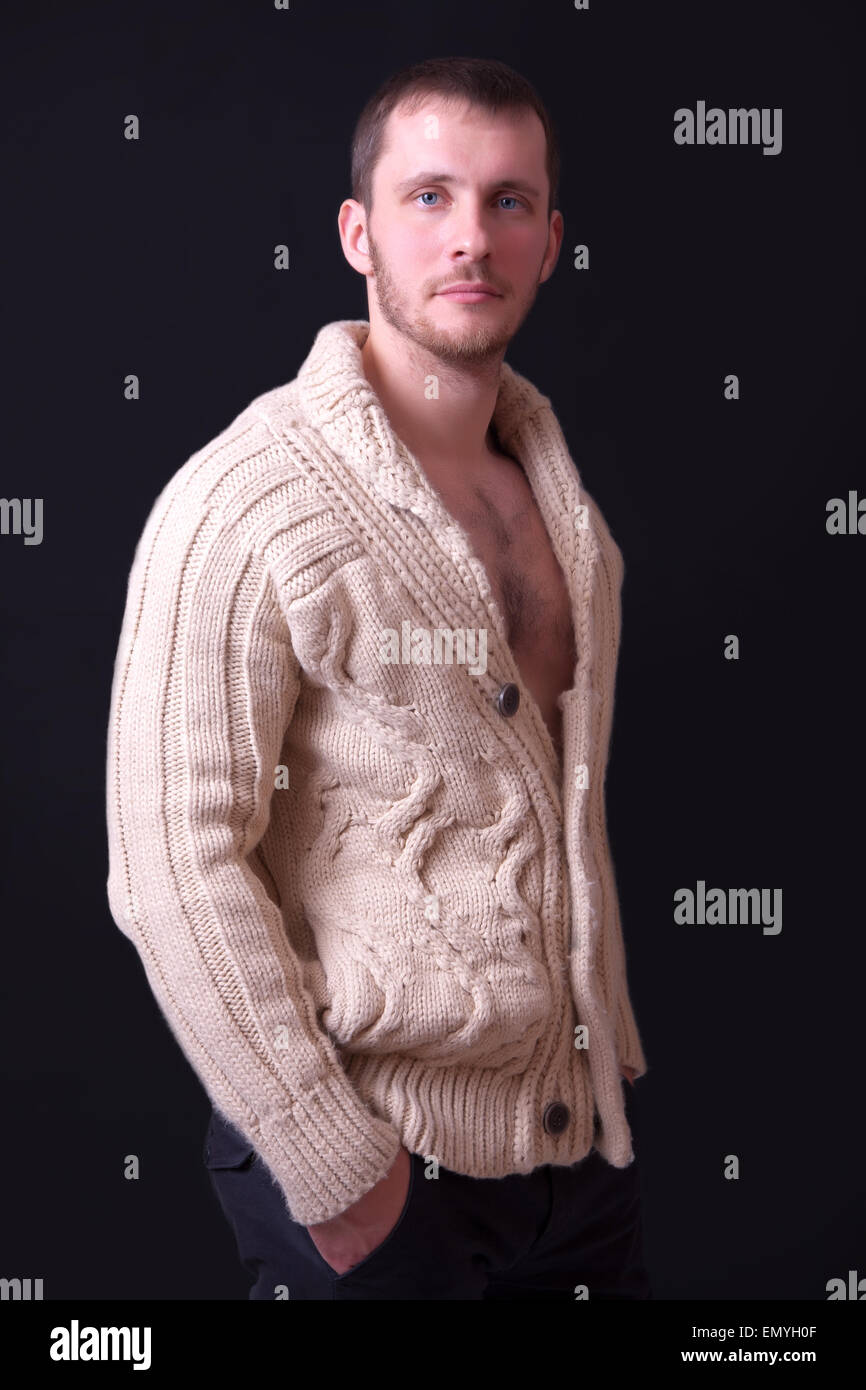 Porträt eines schönen jungen Mannes in einem Pullover, schwarzer Hintergrund Stockfoto