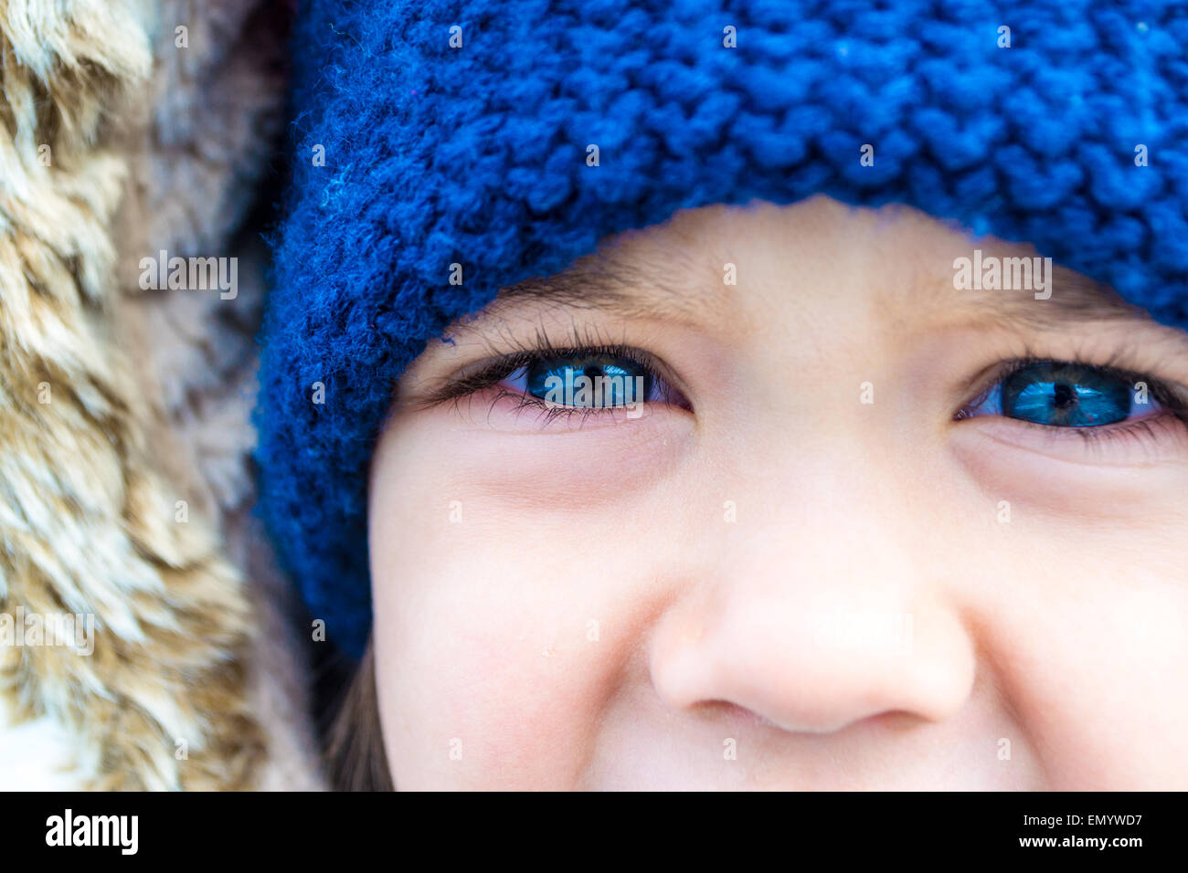 Ein Kind mit blauen Augen in Nahaufnahme mit blaue Wollmütze Stockfoto