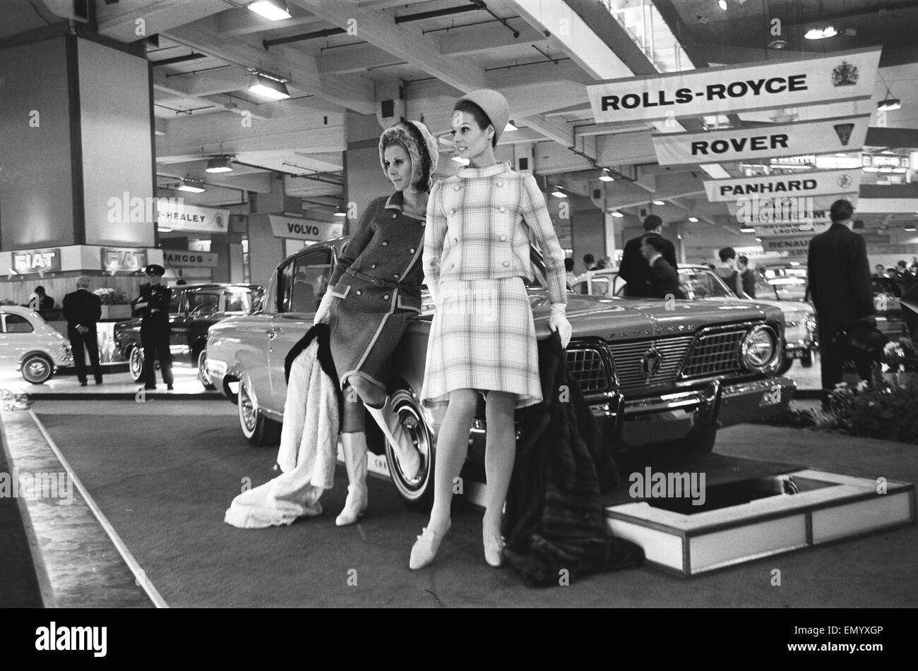 Modelle stellen durch die Motorhaube eines Autos von Plymouth auf der British International Motor Show in London 19. Oktober 1965. Stockfoto