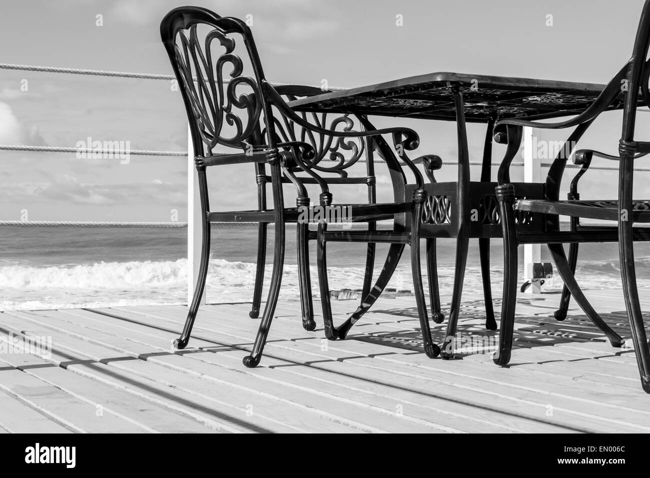 Leere schwarze Gusseisen Stühle und einen Tisch auf hölzernen Planken Stockfoto
