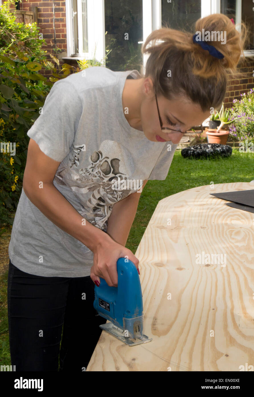 Mädchen-Sägen mit elektrischen Vorrichtung sah Stockfoto