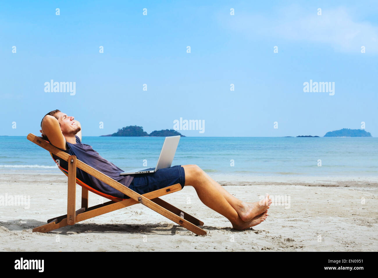 lächelnde Geschäftsmann mit Computer Entspannung am Strand Stockfoto